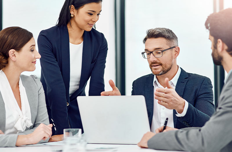 Image of man looking down at a laptop during a meeting