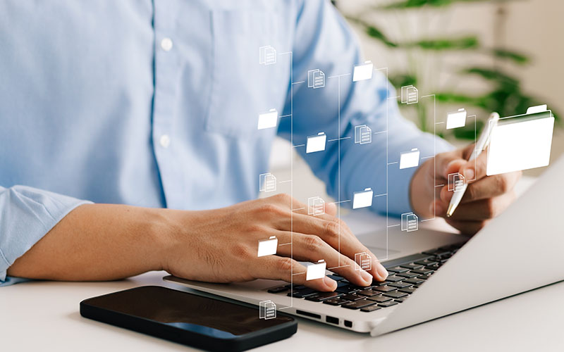 Man working on a laptop with graphic of files