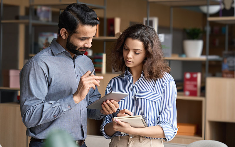 Two collegues looking at a tablet during a meeting