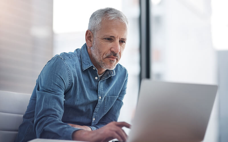 Mature businessman working on laptop computer in bright office