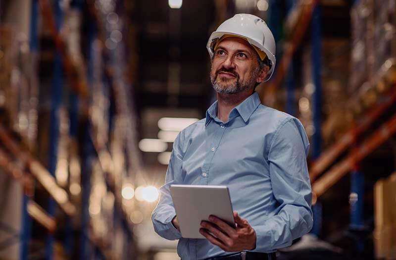 Business manager checking inventory of warehouse on tablet computer