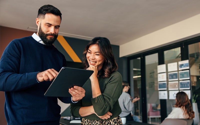 Smiling business professionals on tablet device in office